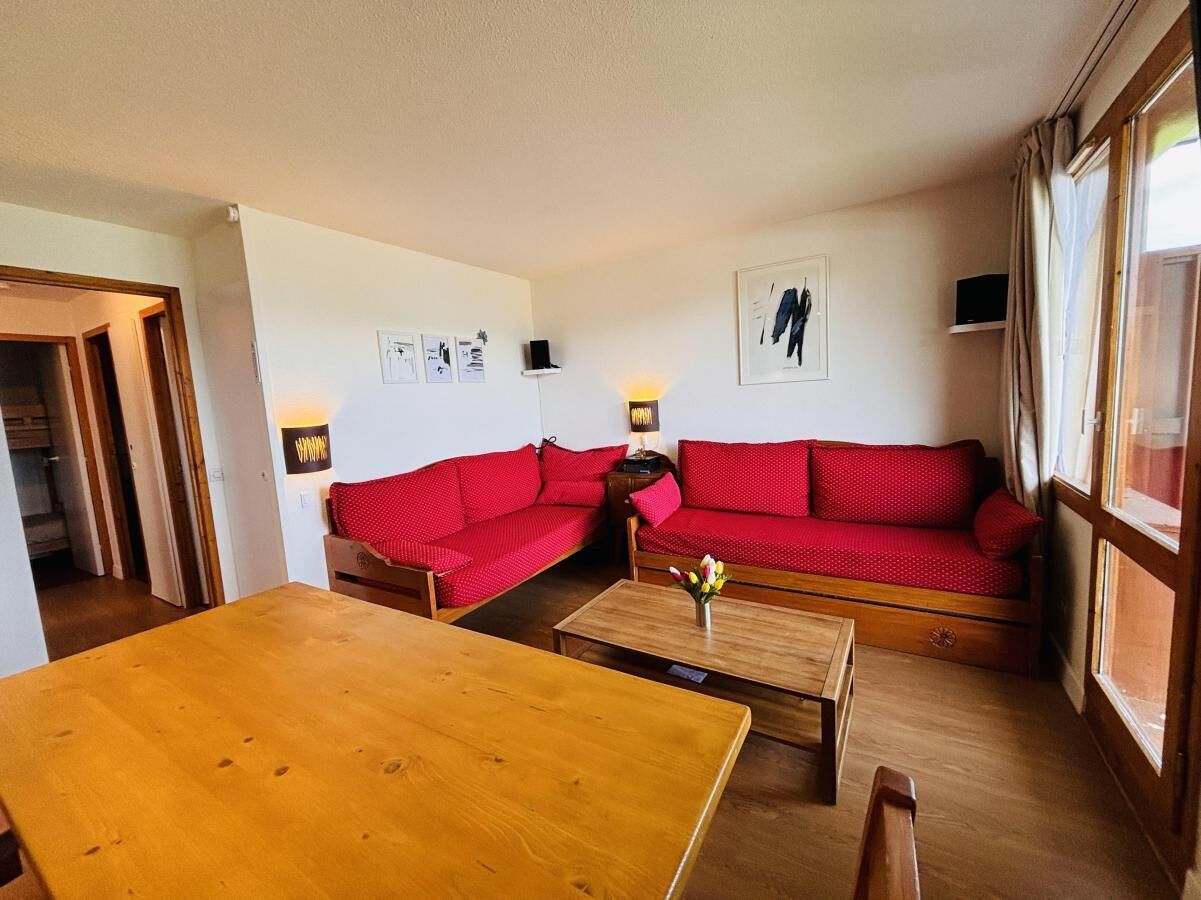 A cozy living room with a wooden table, two red sofas, and a small coffee table.