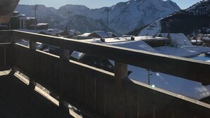 A wooden deck with a view of snow-covered mountains and a clear sky.