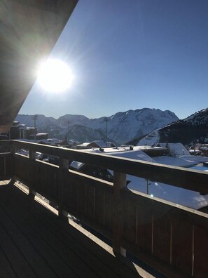 Eine Holzterrasse mit Blick auf schneebedeckte Berge und einen klaren Himmel.