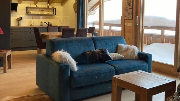 A cozy living room with a blue sofa, a wooden coffee table, and a dog.