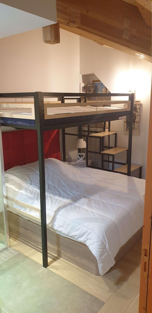 A bunk bed with a desk and shelves, a lamp, and a small window.