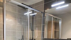 A modern bathroom with a glass-enclosed shower, a vanity with a sink, and a mirror above the vanity.