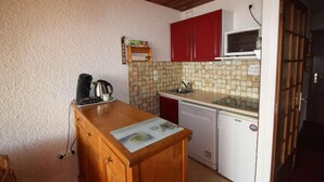 Una cocina compacta con mostrador de madera, un microondas, un lavabo y un lavavajillas.