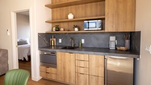 Een kleine keuken met houten kastjes, een roestvrijstalen koelkast en een inbouwmagnetron.