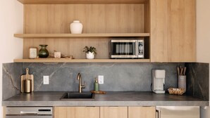 Een moderne keuken met houten planken, een magnetron, een koffiezetapparaat en een vaatwasser.
