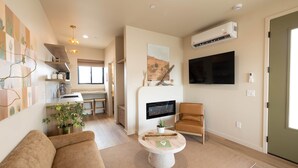 A modern living room with a sofa, a coffee table, a TV, and a fireplace.