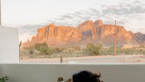 A woman in a bathtub with a view of a desert landscape and mountains.