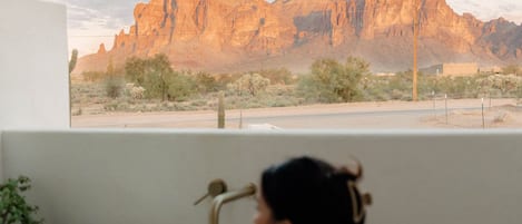Una dona a la banyera amb vista a un paisatge desert i muntanyes.