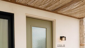 A modern entrance with a frosted glass door, a nameplate, and a textured ceiling.