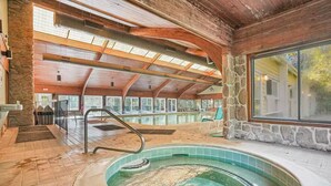 Een wellnessruimte met een bubbelbad, stenen muren en een houten plafond.