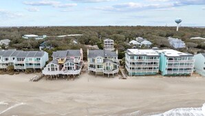 Une propriété située en bord de mer, comprenant plusieurs maisons, dont certaines sont dotées de balcons, et avec un château d’eau en arrière-plan.