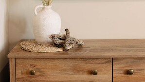 A wooden dresser with a white vase containing dried plants and a woven placemat. - Vega 02: A spacious, 3-bedroom desert oasis stay, Vega #2 (Pinal County)