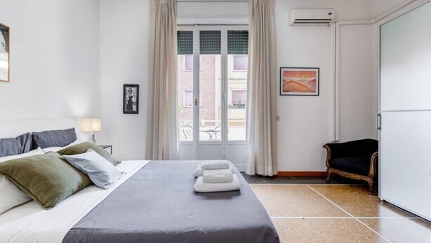 A hotel room with a bed, a chair, a window with curtains, and a picture on the wall. - Elegance&Comfort in Rome-Liberty- (Roma)