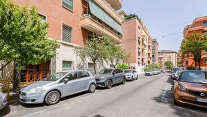 A street lined with multi-story buildings, parked cars, and trees. - Elegance&Comfort in Rome-Liberty- (Roma)