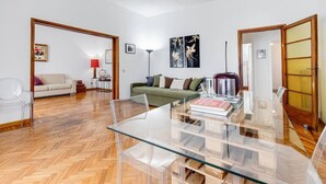A spacious living room with a glass table, a green sofa, and a white couch. - Elegance&Comfort in Rome-Liberty- (Roma)