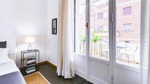A hotel room with a bed, a bedside table with a lamp and books, a window with a view of the outside balcony and buildings. - Elegance&Comfort in Rome-Liberty- (Roma)