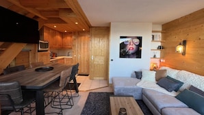 Un accogliente soggiorno con un tavolo da pranzo in legno, un divano e una TV a parete.