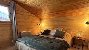 Accogliente camera da letto in una baita di legno, con un letto, lampade sui comodini e una finestra.