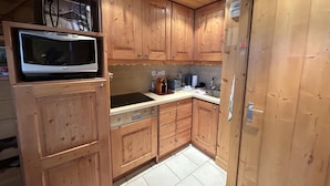 Una cucina compatta con mobili in legno, un forno a microonde integrato e un lavandino.