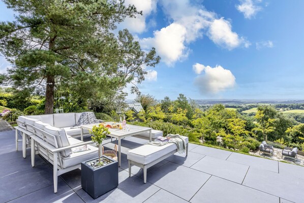 An outdoor patio with a white sofa set, a table, and a potted plant.