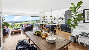 A modern kitchen with a large island, dark cabinets, and a view of the countryside. - Fox Hill House in Haytor (Newton Abbot)