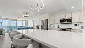 Una cucina moderna con mobili bianchi, elettrodomestici in acciaio inossidabile e una grande isola con sgabelli da bar.