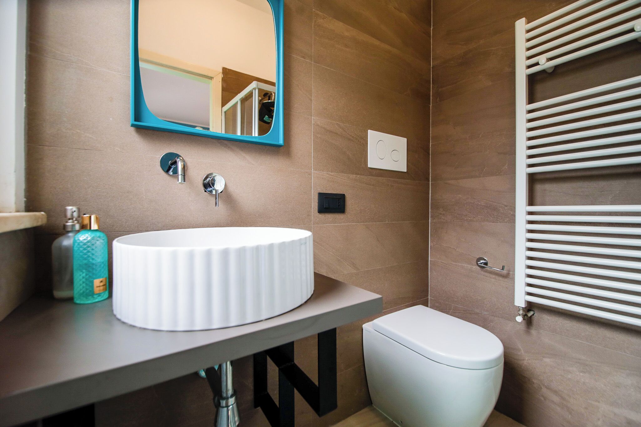 A bathroom with a white sink, a mirror, a toilet, and a towel rack.