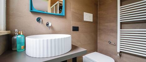 A bathroom with a white sink, a mirror, a toilet, and a towel rack.