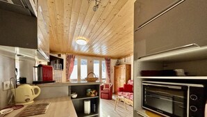 A kitchen with wooden ceiling, a built-in oven, and a dining area with a red sofa. - 4th floor, balcony, tv, 28m², Serre Chevalier (La Salle-les-Alpes)