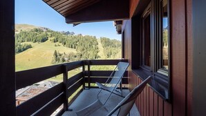 Un balcon donnant sur un paysage montagneux, une chaise et une fenêtre.