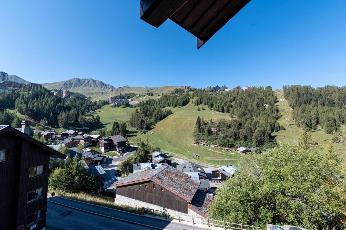Eine gebirgige Landschaft mit einem Dorf aus Häusern und Gebäuden, umgeben von dichten Wäldern und Bergen.