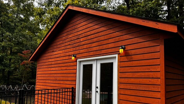 A small, single-story wooden cabin with a white-framed door and a small porch. - Charming tiny home only 15 mins from Town of Warrenton & Town of Culpeper (Rixeyville)