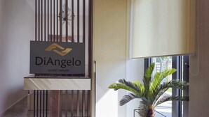 En receptionsområde med et skilt for 'DiAngelo Guest House' og en potteplante.