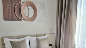 Et hotelværelse med en stor seng, beige sengetøj og en rund dekoration på væggen.
