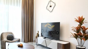 Ein modernes Wohnzimmer mit Flachbildfernseher, einem bequemen Sessel, einem Couchtisch und einer Topfpflanze.