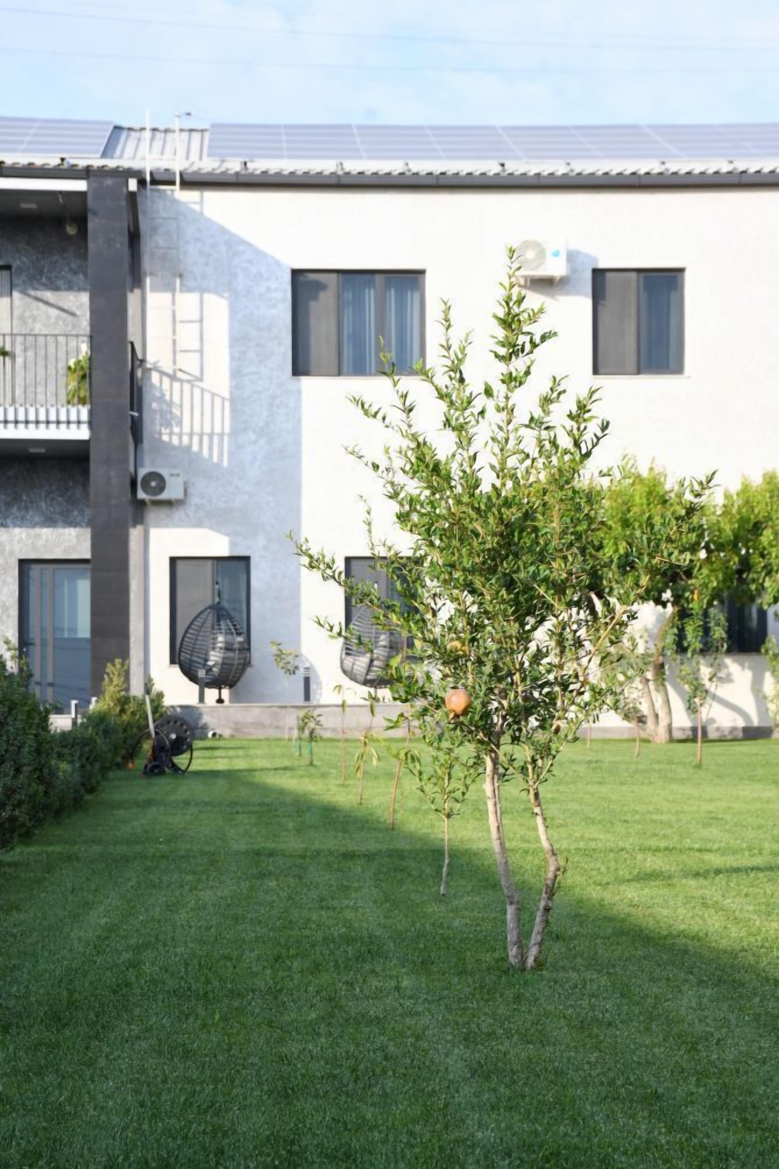 Un bâtiment moderne à deux étages, doté d’un toit plat, de panneaux solaires et d’une pelouse bien entretenue avec un petit arbre.