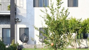 A modern two-story building with a flat roof, solar panels, and a well-maintained lawn with a small tree.