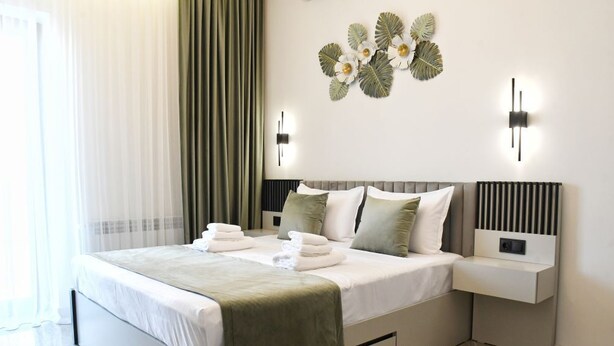 A modern bedroom with a bed, bedside tables, and a decorative wall piece.