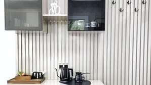 A compact kitchen with a dishwasher, a coffee maker, and a small countertop with a tray and utensils. - DiAngelo Guesthouse|Studio 13 (Yerevan)