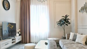 Una sala de estar moderna con un televisor de pantalla plana, un sofá, una mesa de centro y una planta en maceta.