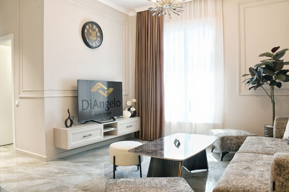 Ein modernes Wohnzimmer mit Flachbildfernseher, Esstisch und einer Couch.
