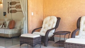 Une pièce meublée de mobilier en osier, dotée d’une cloison en verre et d’un mur à texture.