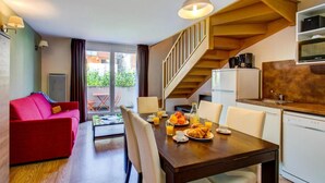 Eine moderne Küche mit einer Holztreppe, einem Essbereich mit Frühstück und einem roten Sofa.