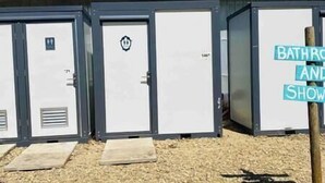 A row of portable restrooms with a sign indicating "bathroom and shower" facilities.