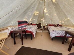 A tent with two beds, a table, and a chair. - #Y6 Wild West- 2 Double beds -Pet friendly, Wild West Yurt 2 Double Beds (Drumheller)