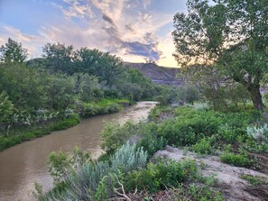 A river flowing through a lush landscape with dense vegetation and hills in the background. - #Y7 Whole New World -2 Dbl beds- No pets please (Drumheller)