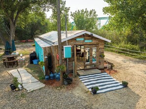 A rustic wooden house with a porch, a covered outdoor seating area, and a gravel driveway. - #Y7 Whole New World -2 Dbl beds- No pets please (Drumheller)