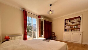 Un dormitorio con una cama grande, una estantería y vistas al exterior.