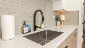A modern kitchen with a stainless steel sink, a black faucet, and a white countertop. - Cozy, Downtown Boise, BSU, Getaway! (Boise)