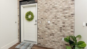 A white door with a number plate, a welcome mat, and a brick wall. - Cozy, Downtown Boise, BSU, Getaway! (Boise)
